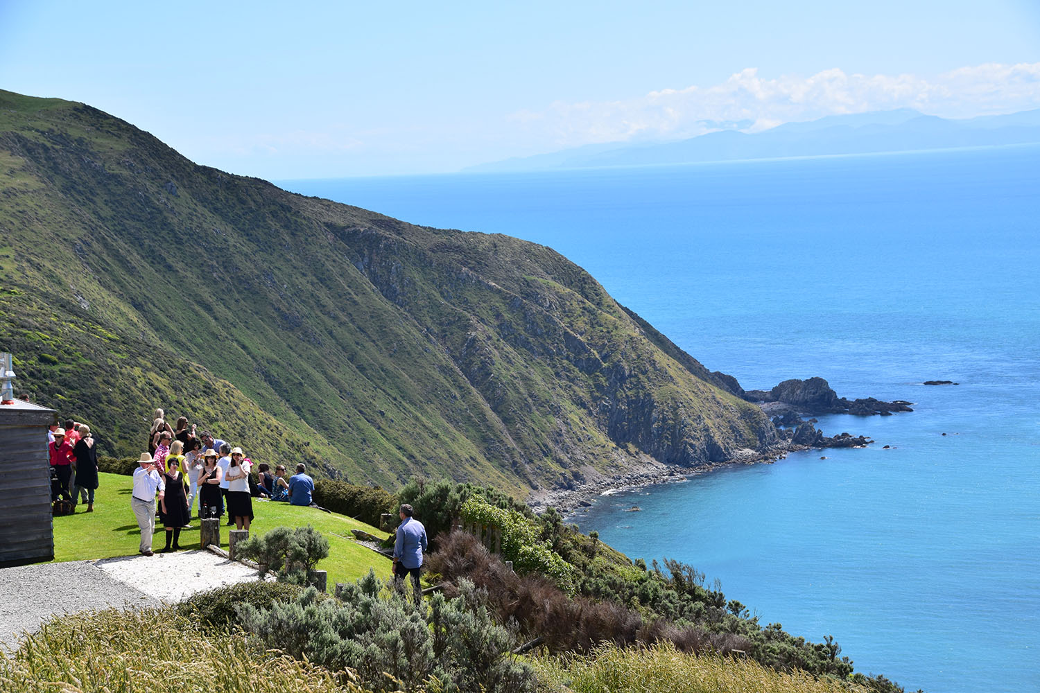Guests enjoying the sunshine out on the lawn during a funtion at The Lodge. Sea and coastal veiws in the distance.